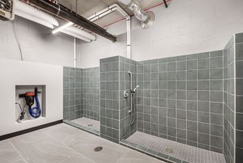 A bathroom with grey tiles and a white wall.